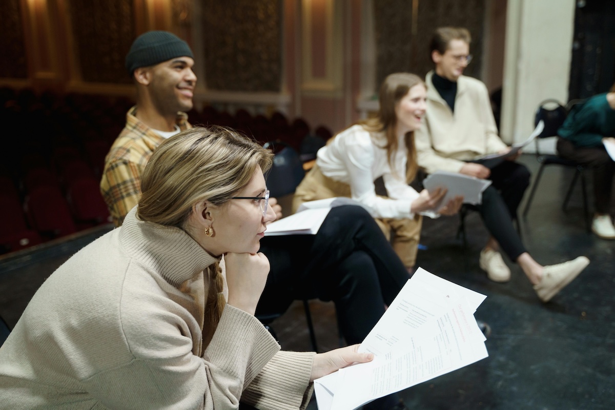 image of four people sat on chairs holding scripts